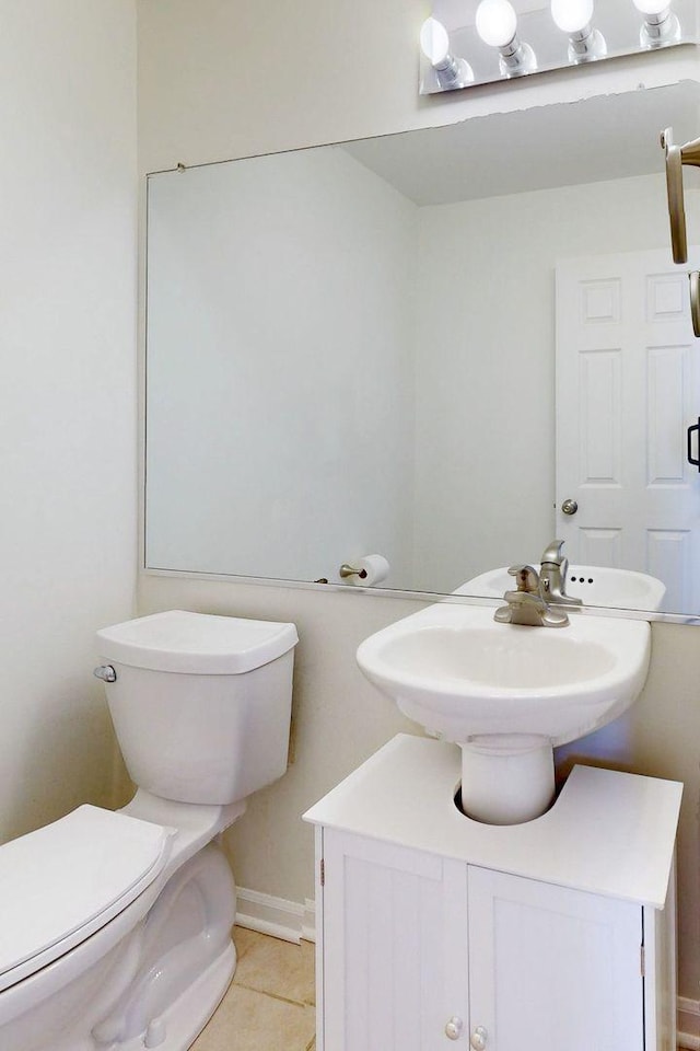 bathroom featuring a sink, toilet, tile patterned flooring, and baseboards
