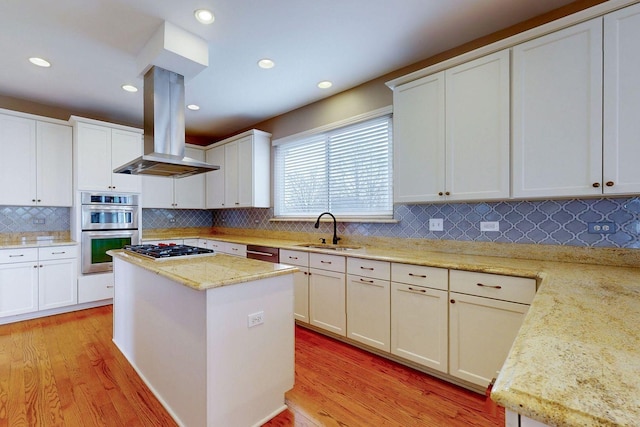 kitchen with a center island, a sink, appliances with stainless steel finishes, light wood finished floors, and island range hood