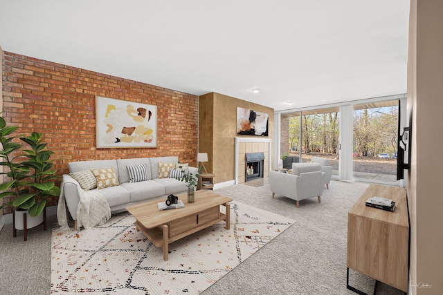 living room featuring brick wall, a tiled fireplace, and carpet
