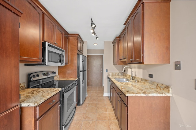 kitchen featuring light tile patterned floors, a sink, light stone countertops, and stainless steel appliances