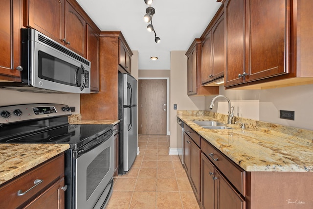 kitchen featuring light tile patterned floors, light stone countertops, a sink, stainless steel appliances, and baseboards