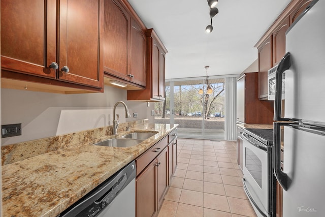 kitchen featuring light tile patterned floors, hanging light fixtures, a sink, appliances with stainless steel finishes, and light stone countertops