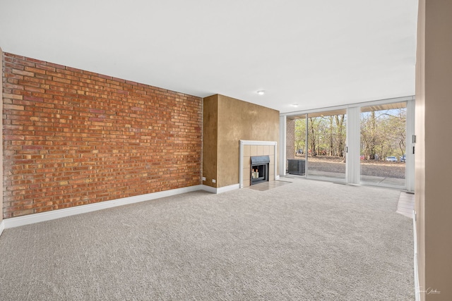 unfurnished living room with baseboards, a tiled fireplace, and carpet
