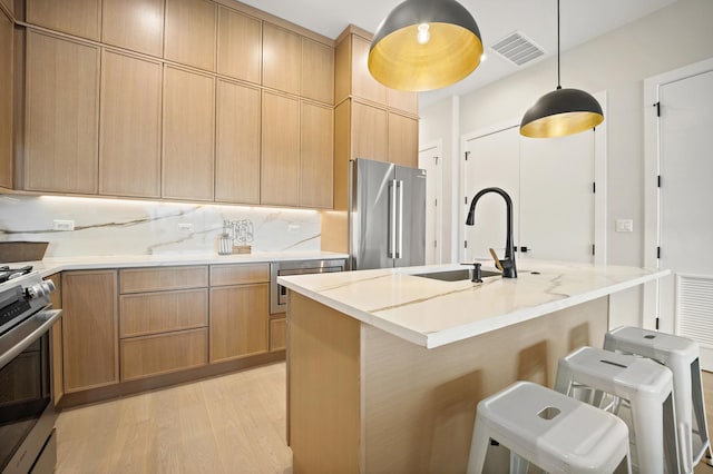 4347 N Richmond Ave Unit 3N, Chicago, IL 60618 - kitchen featuring appliances with stainless steel finishes, a sink, light wood-style flooring, a breakfast bar area, and hanging light fixtures