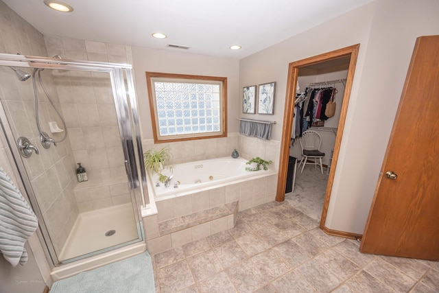 full bathroom with a shower stall, a spacious closet, visible vents, and a tub with jets