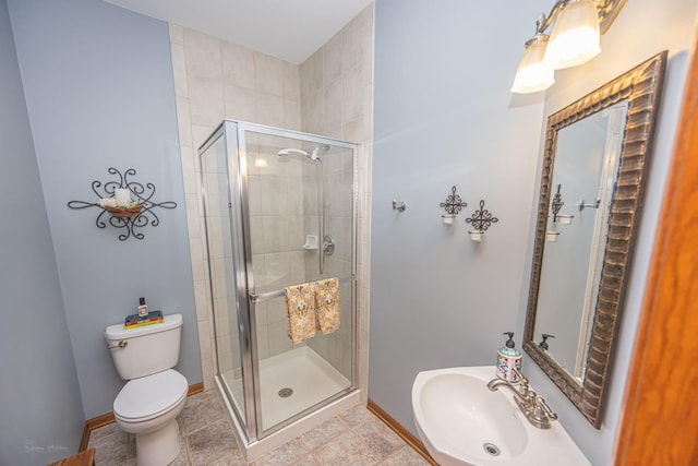 bathroom featuring a shower stall, a sink, baseboards, and toilet