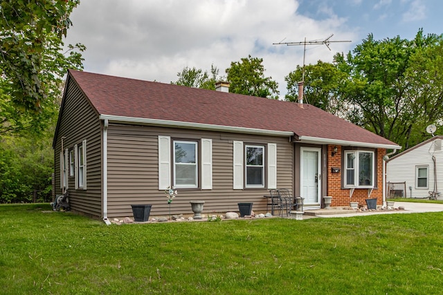 bungalow-style home featuring a front lawn, a chimney, a shingled roof, and brick siding