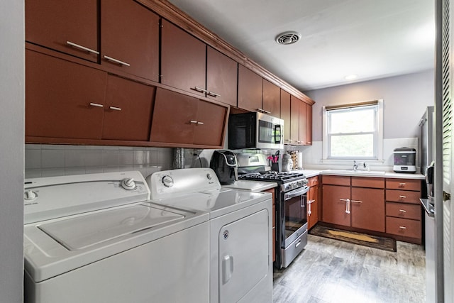 laundry area featuring washer and clothes dryer and light wood finished floors