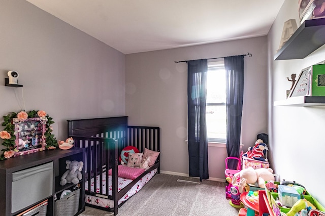 bedroom with carpet floors, baseboards, and a crib