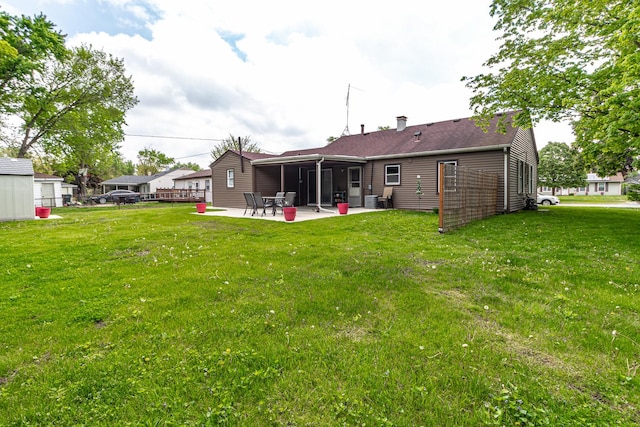 rear view of property with a patio, a yard, and a chimney