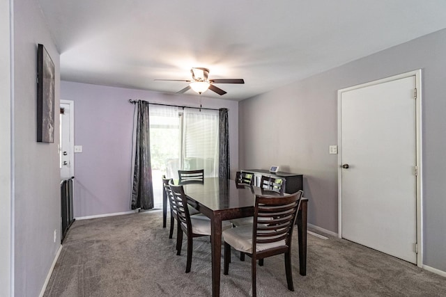 carpeted dining space featuring ceiling fan and baseboards