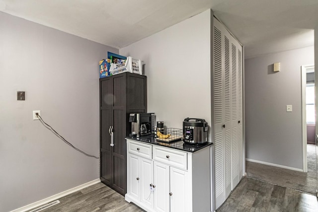 kitchen with wood finished floors, dark countertops, and baseboards