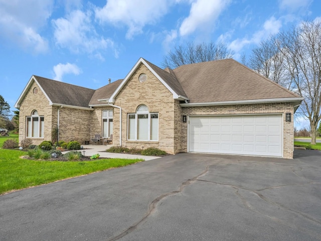 ranch-style home with roof with shingles, an attached garage, aphalt driveway, and brick siding