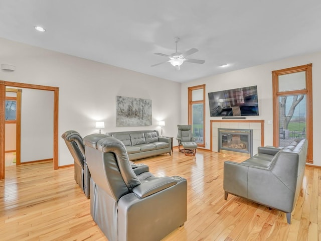 living room with ceiling fan, recessed lighting, baseboards, light wood-type flooring, and a tile fireplace