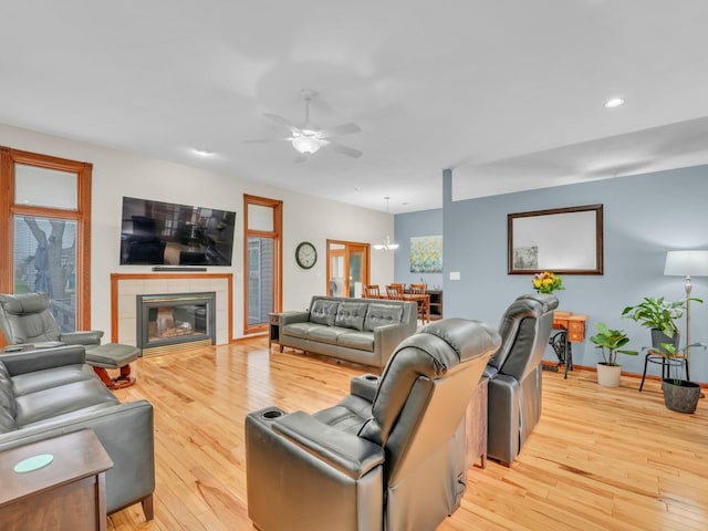 living room with recessed lighting, light wood finished floors, ceiling fan with notable chandelier, and a fireplace