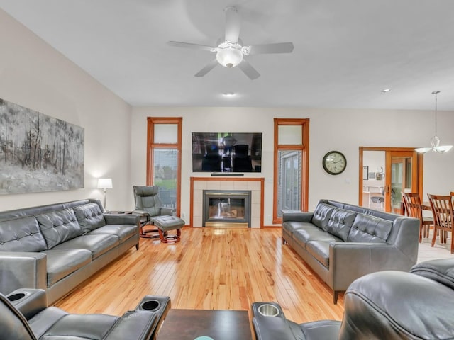 living area featuring wood-type flooring, a ceiling fan, and a tile fireplace