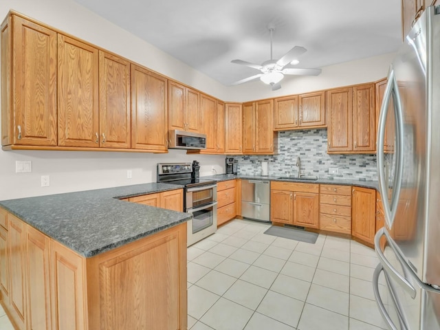 kitchen featuring ceiling fan, appliances with stainless steel finishes, a sink, a peninsula, and light tile patterned floors