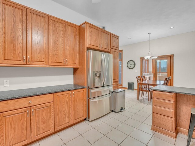 kitchen with hanging light fixtures, light tile patterned floors, stainless steel fridge with ice dispenser, dark stone countertops, and a notable chandelier