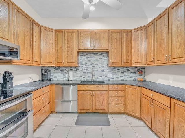 kitchen with ceiling fan, backsplash, appliances with stainless steel finishes, a sink, and light tile patterned floors