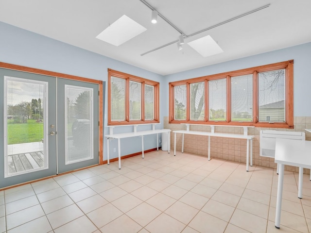 unfurnished sunroom with a skylight, plenty of natural light, and rail lighting