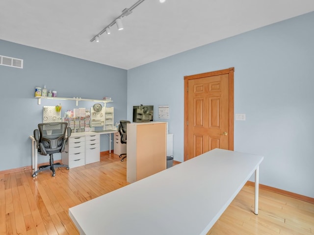 office featuring light wood-style floors, baseboards, rail lighting, and visible vents