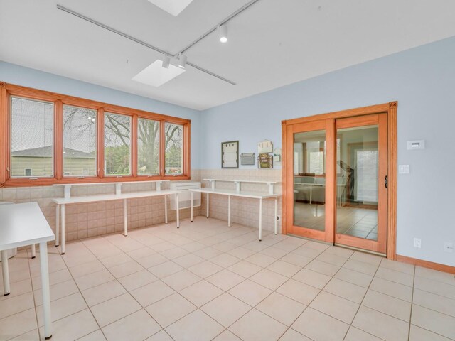 unfurnished room featuring track lighting, light tile patterned floors, and a skylight