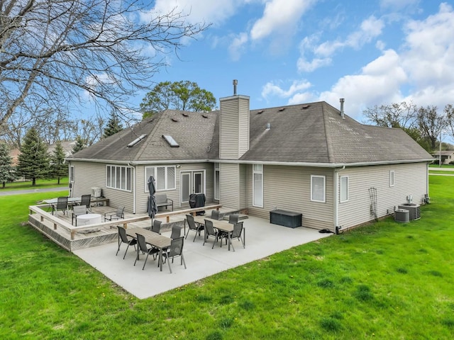 back of house with a chimney, a shingled roof, a patio area, a lawn, and central air condition unit