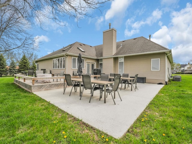 rear view of house with a lawn, a chimney, outdoor dining area, and a patio area