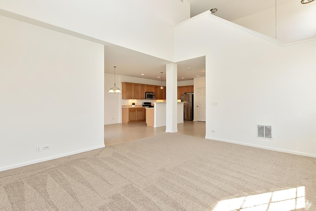 unfurnished living room featuring a towering ceiling, baseboards, light carpet, light tile patterned floors, and visible vents