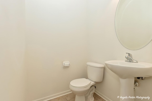 half bathroom featuring toilet, tile patterned flooring, and baseboards