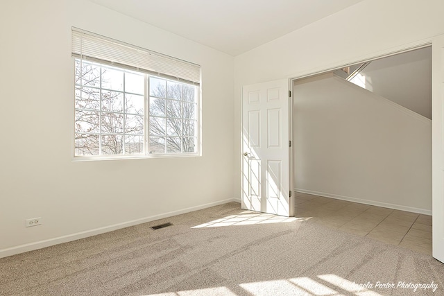 carpeted spare room featuring baseboards and visible vents