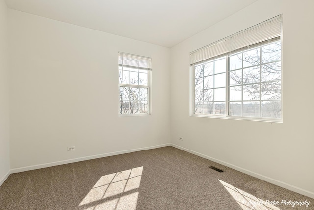 carpeted spare room with visible vents and baseboards