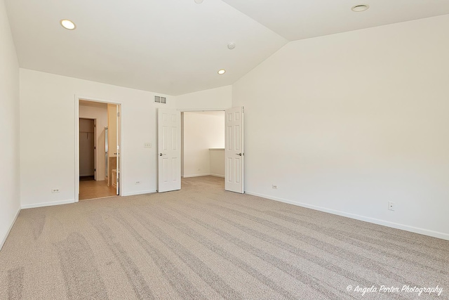 unfurnished bedroom featuring visible vents, baseboards, light colored carpet, and lofted ceiling