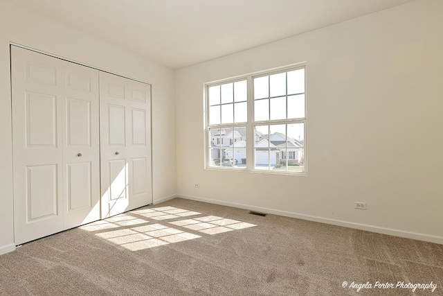 unfurnished bedroom with a closet, carpet flooring, baseboards, and visible vents