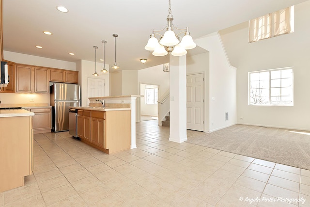 kitchen with an inviting chandelier, open floor plan, light countertops, appliances with stainless steel finishes, and light colored carpet