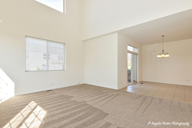 spare room featuring light carpet, plenty of natural light, and a notable chandelier