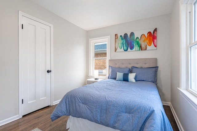 bedroom with multiple windows, baseboards, and wood finished floors