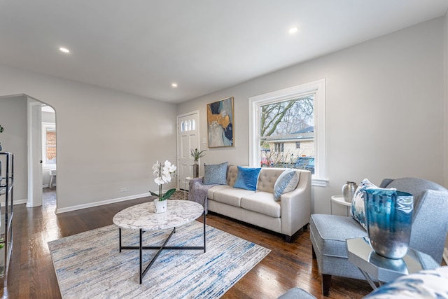 living area with baseboards, recessed lighting, arched walkways, and dark wood finished floors