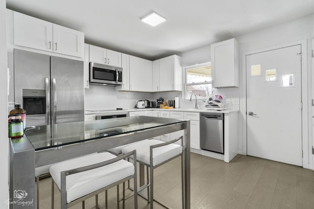 kitchen with light countertops, light wood-style flooring, white cabinetry, and stainless steel appliances