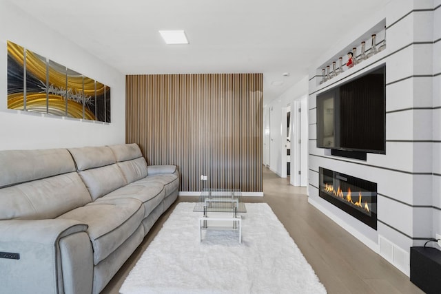 living room with baseboards, a glass covered fireplace, and wood finished floors