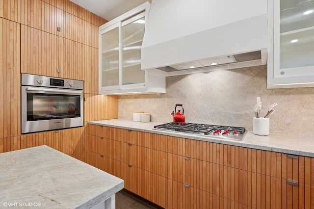 1333 N Bell Ave, Chicago, IL 60622 - kitchen featuring stainless steel appliances, premium range hood, tasteful backsplash, glass insert cabinets, and light stone countertops