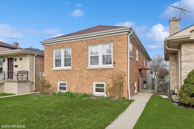 view of side of property with a gate, a yard, brick siding, and fence