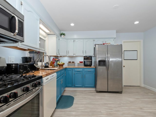 11554 S Neenah Ave, Worth, IL 60482 - kitchen featuring stainless steel appliances, blue cabinets, a sink, light wood-style floors, and wooden counters