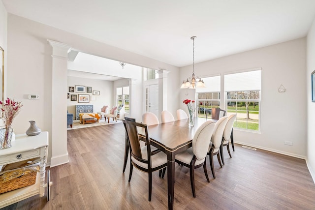 dining room featuring baseboards, ornate columns, and wood finished floors