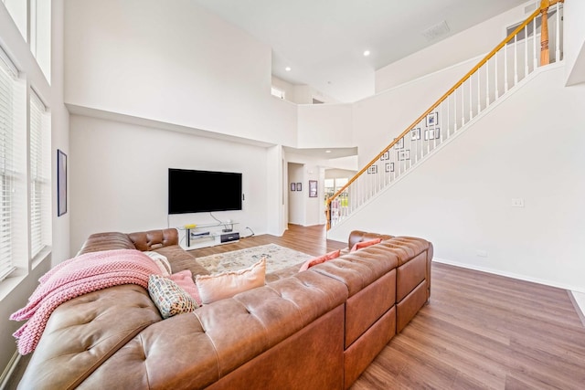 living room with baseboards, a high ceiling, recessed lighting, stairway, and wood finished floors