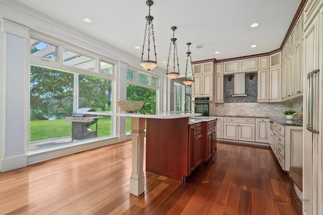 2426 Lexington Dr, Long Grove, IL 60047 - kitchen with wall chimney range hood, stainless steel oven, cream cabinets, backsplash, and dark wood finished floors