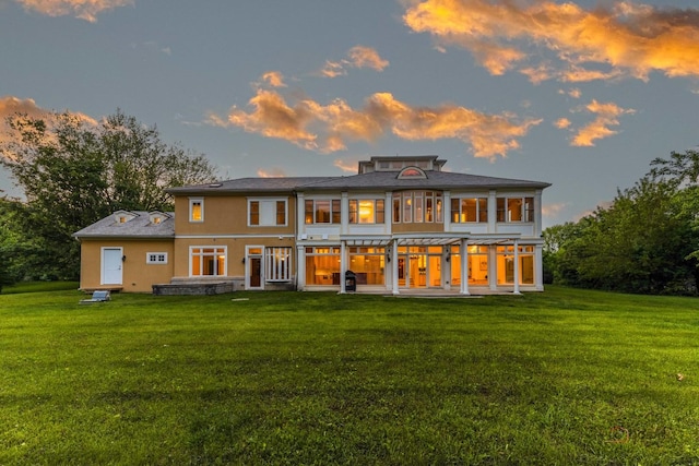 2426 Lexington Dr, Long Grove, IL 60047 - back of house at dusk with a lawn, stucco siding, and a patio area