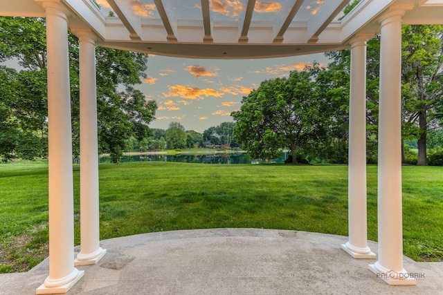 2426 Lexington Dr, Long Grove, IL 60047 - patio terrace at dusk featuring a water view, a patio, a lawn, and view of wooded area