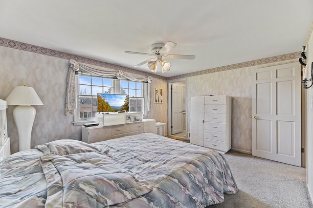 carpeted bedroom featuring wallpapered walls and a ceiling fan