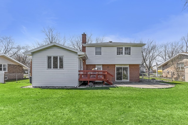 back of house featuring fence, a wooden deck, and a lawn